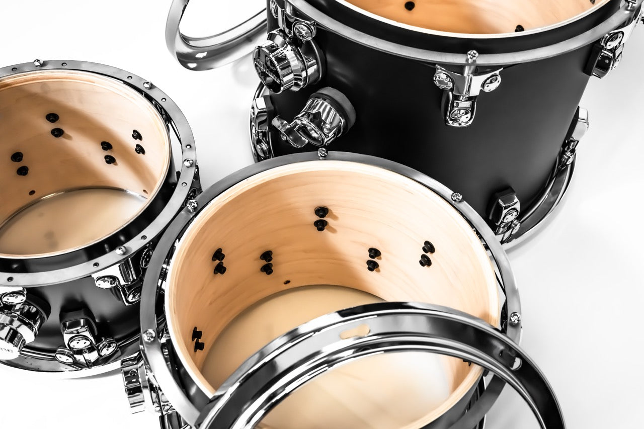 Close-up of a drum set with black and beige drums on a white background